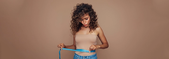 A woman measuring her waist.