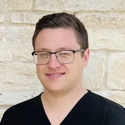 Dr. Logan Hengst smiling in front of a stone wall.